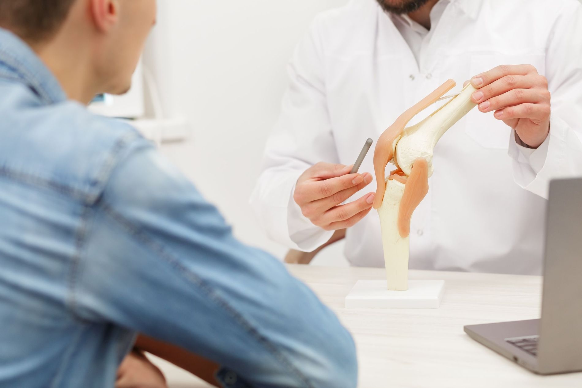 Arzt zeigt einem Patienten ein Kniemodell